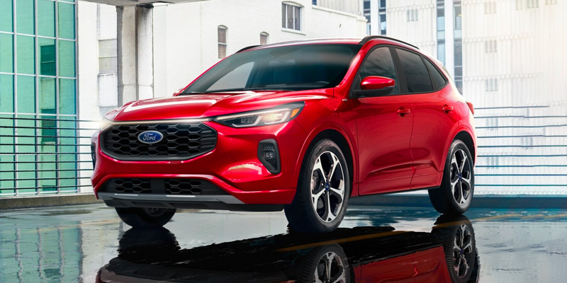 A red Ford Escape sitting before a full-length and full-height window in a dealer showroom.