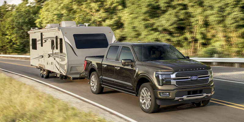 A Ford F-150 towing a camping trailer down the highway