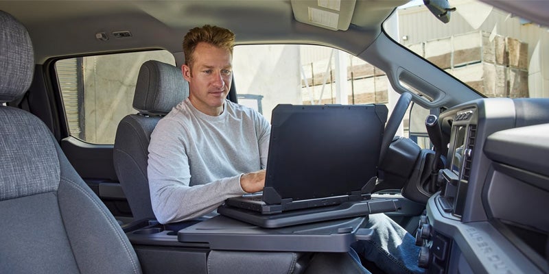 A man getting work done on a laptop in the spacious, technology-filled F-250 cabin